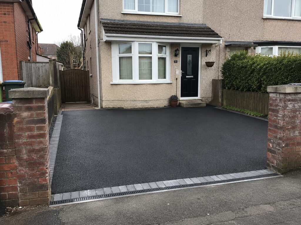 Freshly installed residential tarmac driveway outside a semi-detached house in South Wales with block paving edging and drainage channel.